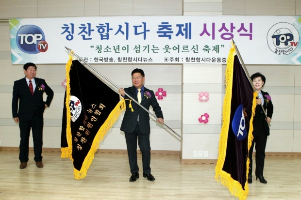 2회 강동구 상일동편에서 3회 평택시로 행사가 이어진다는 의미로 칭찬합시다 기발을 신무연 강동구의원이 유병만 전국회의원에게 전달하고 있다.