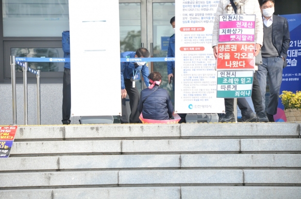 화수화평재개발조합의 한 조합원이 시청 본관현관 앞에서 피켓시위를 하고 있다.