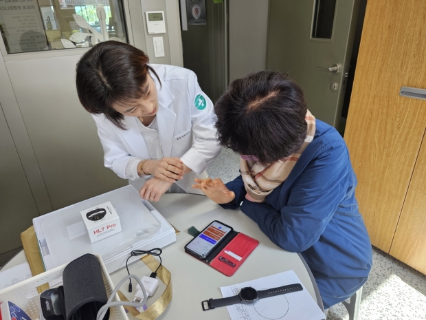 경주시 보건소 공무원이 ‘AI IoT 기반 어르신 건강관리사업’의 일환으로 지급된 손목밴드형 활동량계에 대해 설명하고 있다.