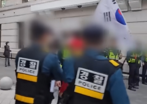 지난 11일 서울 명동에서 반중 시위에 나선 시민들이 집회 장소 밖에서 중국 관광객들과의 충돌을 우려해 태극기를 내리라고 요구하는 경찰과 실랑이를 벌이는 모습/TV조선 뉴스 캡처