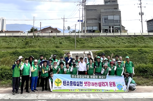 김해시새마을회 회원들이 25일 전하동 강동교 인근 해반천에서 ‘탄소중립 실천 샛강 살리기’ 활동을 펼친 뒤 기념촬영을 하고 있다./사진=김해시
