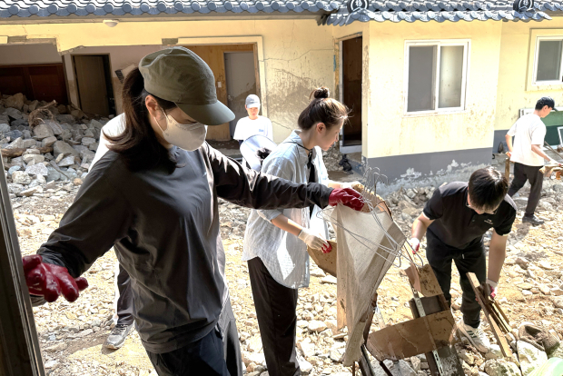 김해문화관광재단 직원들이 집중호우로 피해를 입은 거제시 거제면 벽수암에서 무너진 창고 주변의 잔해를 치우며 복구 작업을 벌이고 있다./사진=김해시