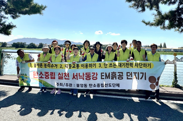 김해시 불암동 탄소중립선도단체 회원들이 8일 서낙동강 일원에서 수질 개선과 하천 생태계 회복을 위한 EM흙공 던지기 캠페인을 펼친 뒤 기념촬영을 하고 있다./사진=김해시